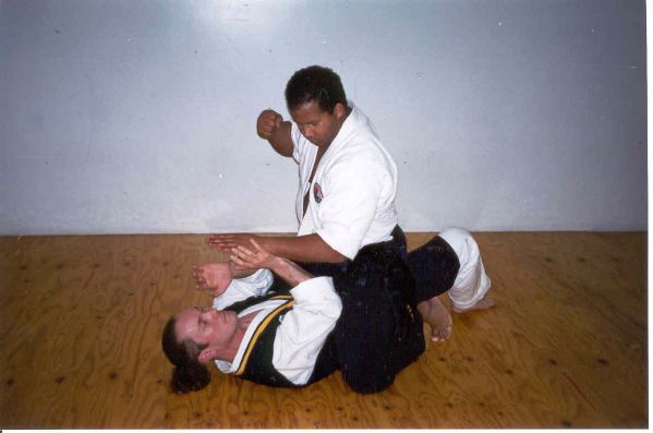 B01- As Inst. King chambers for a punch, Master Wachsmann ties up the other hand and pushes him down onto his hip using his elbows  